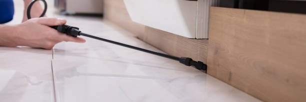 close up of a pest control worker's hand spraying pesticide on wooden cabinet